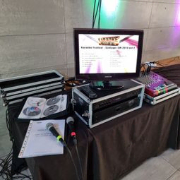 Karaokemaskin på bord med monitor, mixerbord, låtlista och mikrofoner