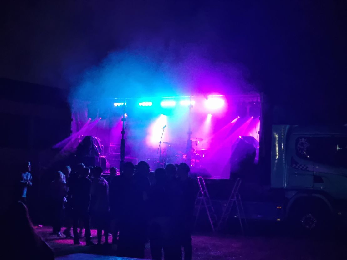 Liveband på scen framför publik med discoljus och rök